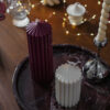 Duo de bougies cylindriques sculpturales Ysadena, blanc crème et bordeaux, posé sur un plateau en marbre