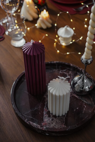 Duo de bougies cylindriques sculpturales Ysadena, blanc crème et bordeaux, posé sur un plateau en marbre