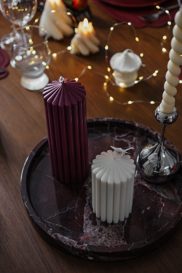 Duo de bougies cylindriques sculpturales Ysadena, blanc crème et bordeaux, posé sur un plateau en marbre