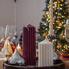 Bougies cylindriques Ysadena en cire végétale, blanc crème et bordeaux, mises en scène devant un sapin de Noël
