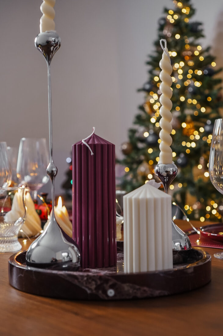 Bougies cylindriques Ysadena en cire végétale, blanc crème et bordeaux, mises en scène devant un sapin de Noël