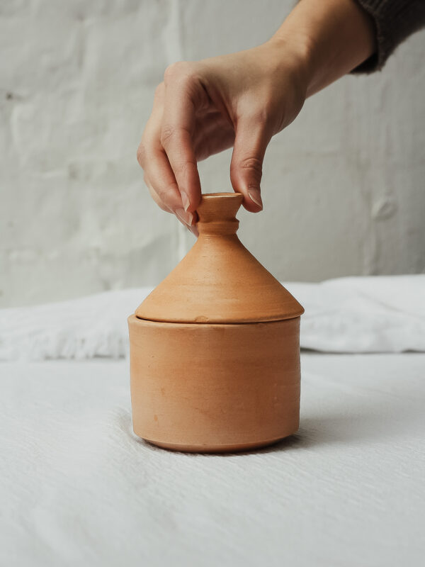 Bougie Inoubliable dans un décor naturel. Bougie Inoubliable dans son pot de tajine, entourée d'éléments naturels.