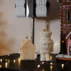 Bougies sculpturales Maison d’Hiver et Casse-Noisette posées sur un meuble avec guirlande lumineuse